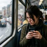 Kobieta w autobusie miejskim czyta na smartfonie podejrzaną wiadomość SMS od banku